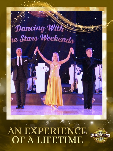 Three ballroom dancers on a stage, the woman in a yellow gown raising her arms with two men on either side; backdrop reads 'Dancing With the Stars Weekends' and a gold frame with the caption 'An Experience of a Lifetime.'