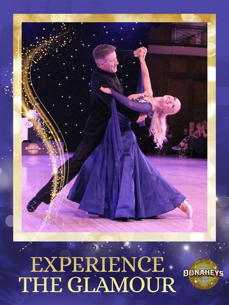 Ballroom dancing couple on stage; woman in a blue gown is dipped by a man in black, framed by a gold border with 'EXPERIENCE THE GLAMOUR' text on an event poster.